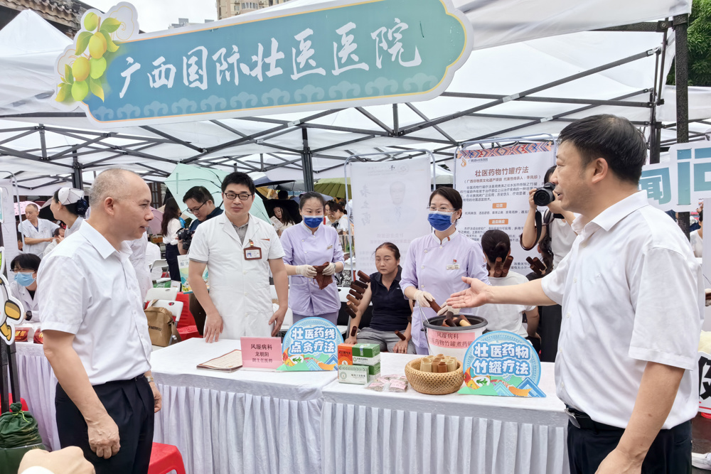 自治区中医药局党组书记、局长黎甲文（左一），广西国际壮医医院党委书记秦祖杰（右一）到国壮展台参观指导。